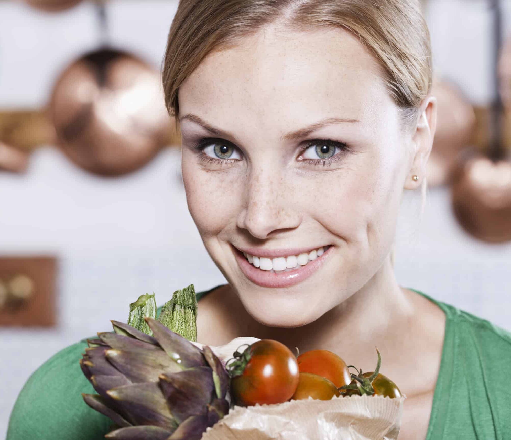 Italy, Tuscany, Magliano, Close up of young woman holding bag of vegetables